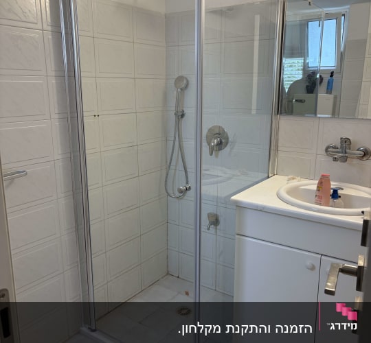 מקלחון זכוכית עם ראש מקלחת וכיור בחדר אמבטיה